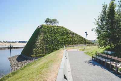 Footpath by river against clear sky