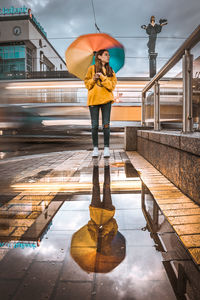 Full length of woman standing by railing during rainy season