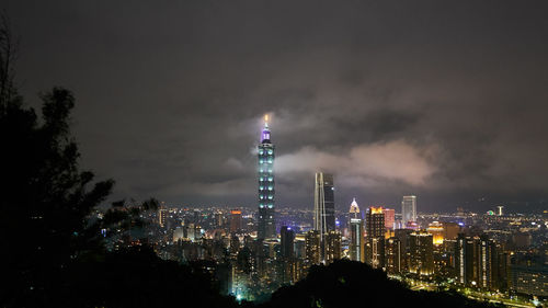 Illuminated buildings in city against sky at night