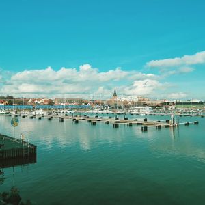 Boats in marina by buildings against blue sky