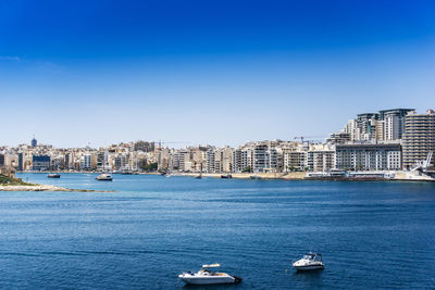 Yacht moored in sea by buildings against clear sky