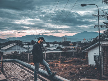 Man standing by houses against sky