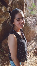Portrait of smiling young woman standing against rock formations