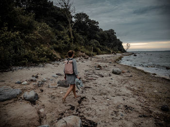 Rear view of friends on beach against sky