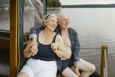 Happy senior couple sitting with arm around on houseboat