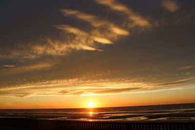 Scenic view of sea against dramatic sky during sunset