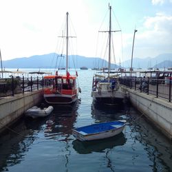 Boats moored at harbor against sky