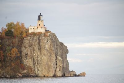 Lighthouse by sea against sky