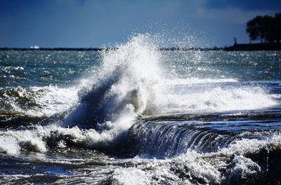 Waves splashing on sea against sky