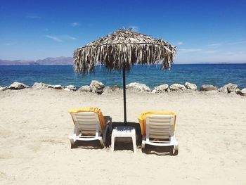 Deck chairs on beach against sky