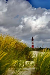 Lighthouse on field against sky