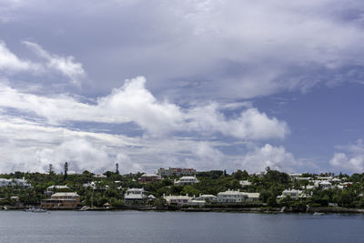 Buildings by river against sky in city