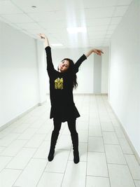 Portrait of happy teenage girl posing in illuminated white university corridor