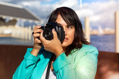 Portrait of young woman photographing through camera