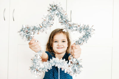 Portrait of smiling girl with christmas decoration against white background