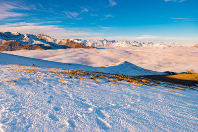 Distant view of woman hiking on snowcapped mountain