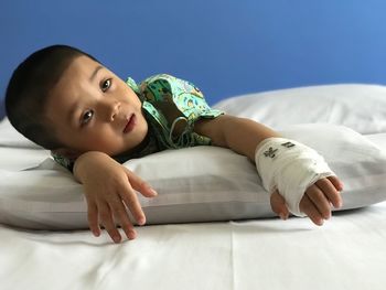 Portrait of girl with bandage on hand lying in bed at home