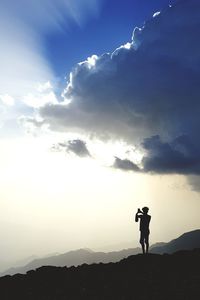 Silhouette man standing on mountain against sky