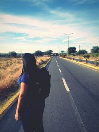 Rear view of woman standing on road against sky