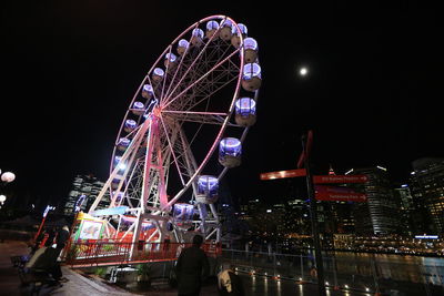 Low angle view of illuminated ferris wheel against sky at night