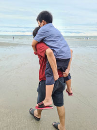 Rear view of friends standing on beach