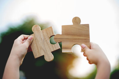 Cropped hand holding jigsaw puzzle on table