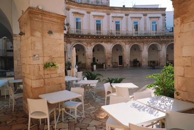 Empty chairs and tables in cafe amidst buildings