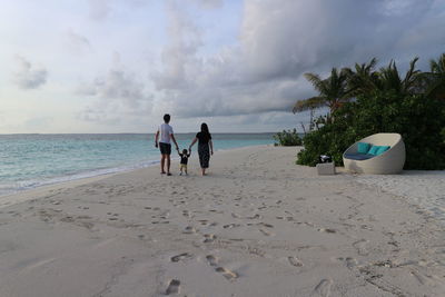 Rear view of people on beach against sky