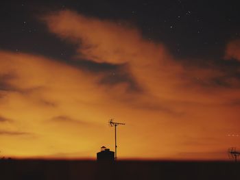 Silhouette antenna against orange sky