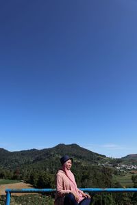 Portrait of man standing on mountain against clear blue sky