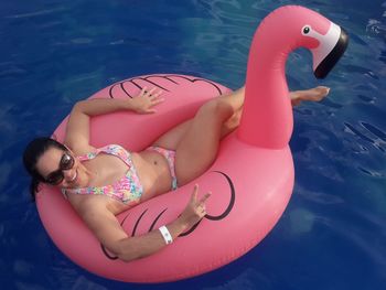 Portrait of woman wearing sunglasses in inflatable ring floating on water