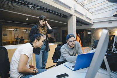 Computer programmers using laptop at desk in office