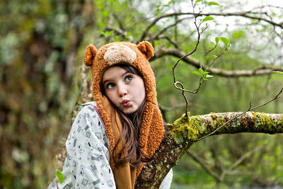 Girl wearing knit hat puckering lips by tree in forest