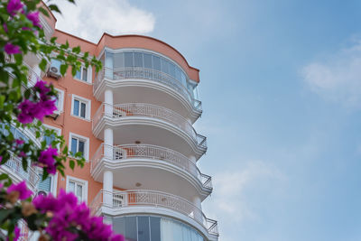 Forged white metal balconies on the facade of a residential building against the sky.