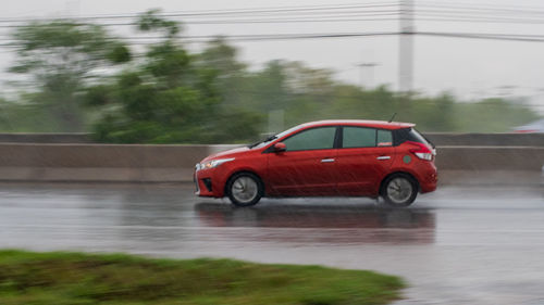 Red car on road during rainy season