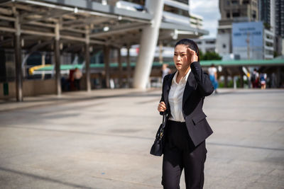 Businesswoman standing on street against building