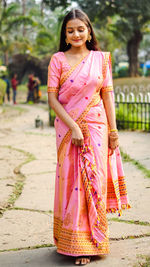 Young woman standing against pink umbrella