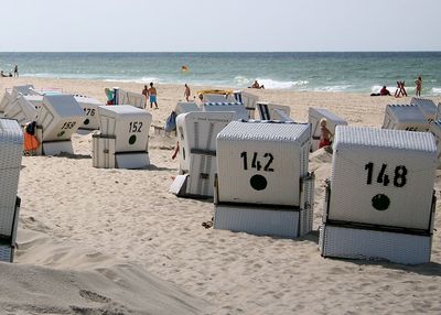 Hooded beach chairs on beach against clear sky