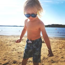 Boy wearing sunglasses on beach against sky