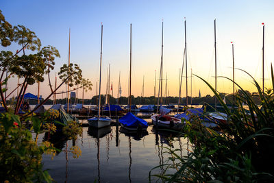 Boats moored in harbor at sunset