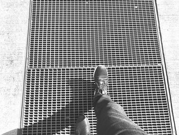 Low section of man standing on metal grate