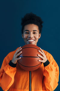 Man playing basketball while standing against blue sky