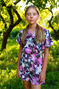 Portrait of young woman standing against tree