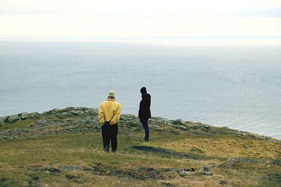 Men standing on hill against sea