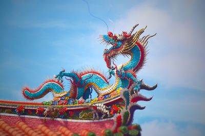 Low angle view of dragon sculpture against sky