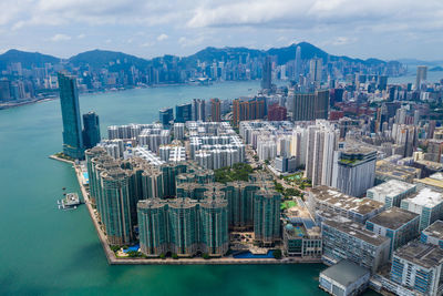 Aerial view of city by sea against sky