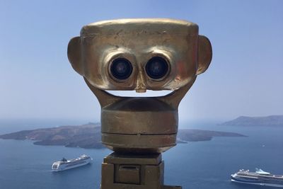 Close-up of coin-operated binoculars by sea against sky