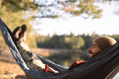 Happy man day dreaming while relaxing on hammock in forest