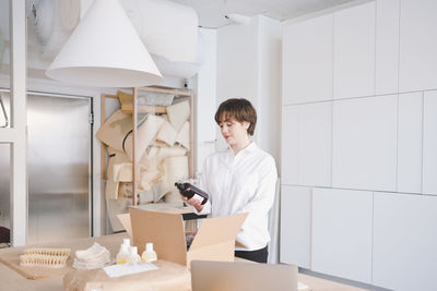 Young female craftsperson holding bottle in workshop