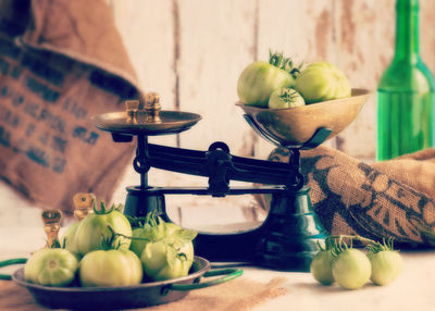 Green tomatoes in weight scale on table